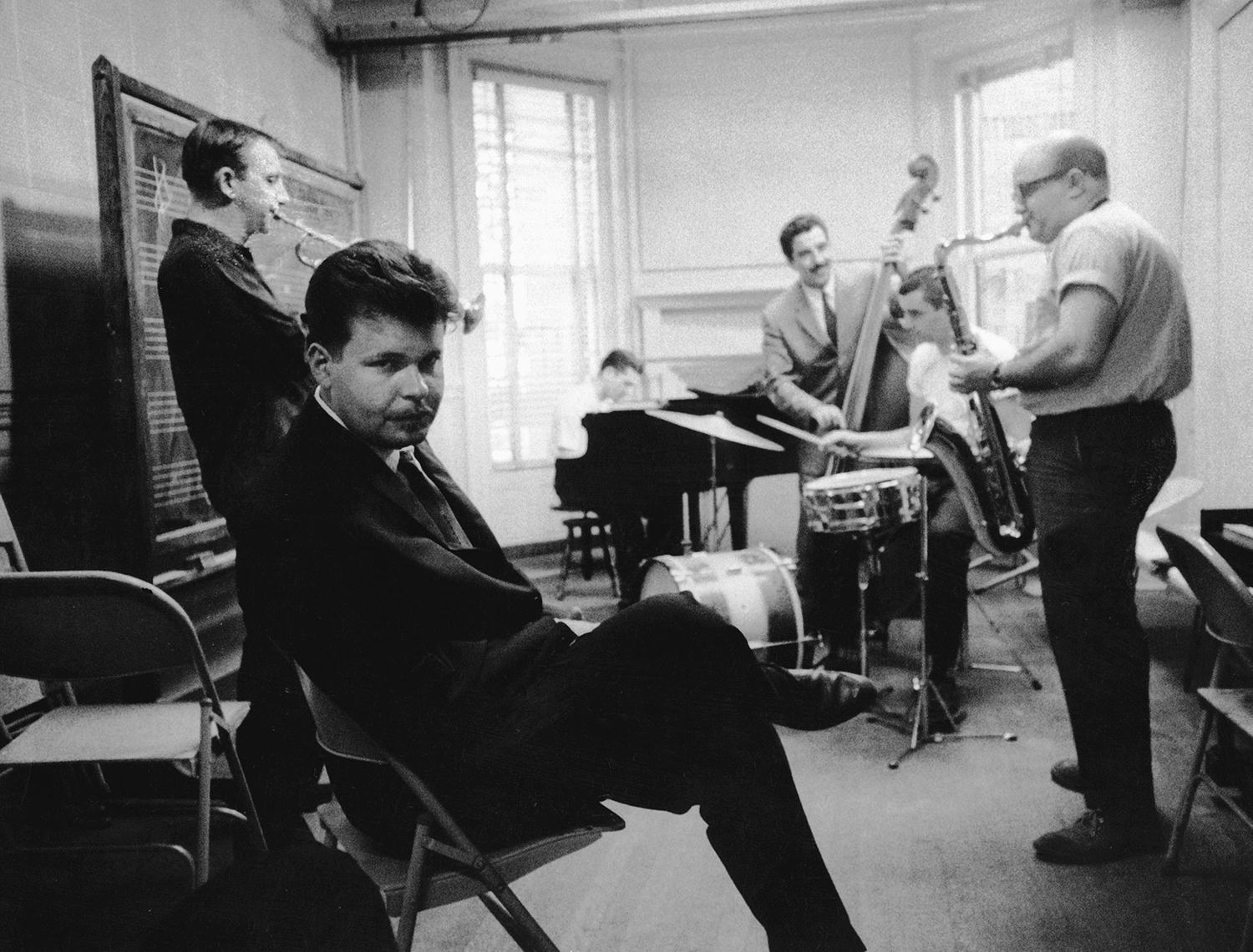 Black and white photograph of men in a practice room rehearsing their quintent act.