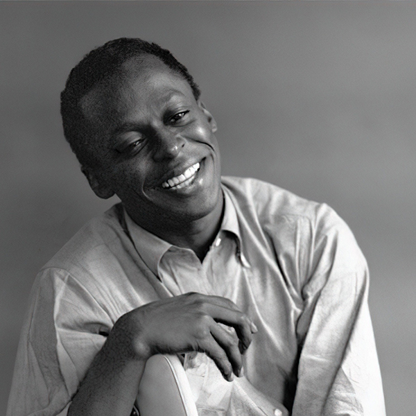 Black and white portrait of Miles Davis smiling, tilting his head