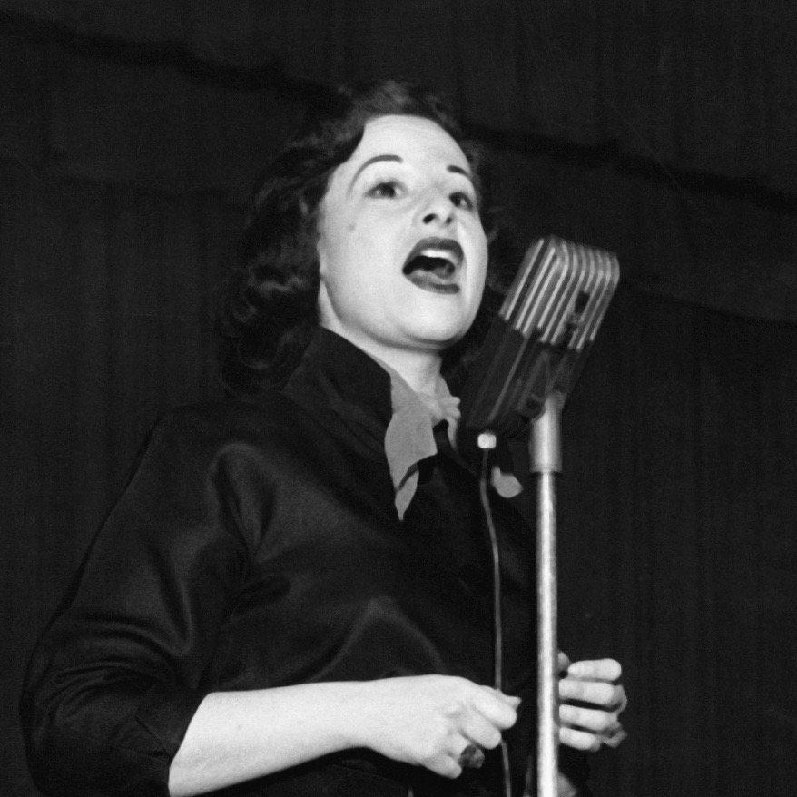 Black and white photograph of jazz singer Teddi King in front of a microphone.
