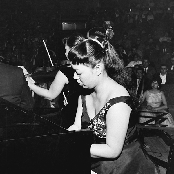 Black and white photograph of Toshiko Akiyoshi performing her Jazz Suite for Orchestra at a piano as a student in 1957.