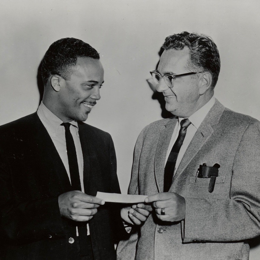 Photograph of Quincy Jones presenting Lawrence Berk with a check.
