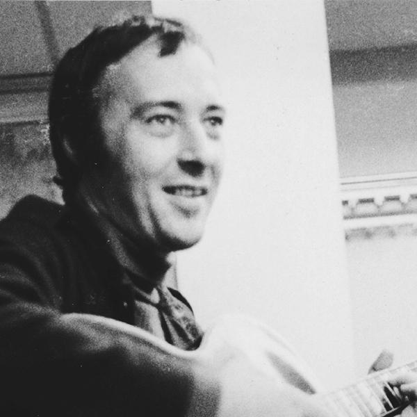 Black and white portrait of Gábor Szabó playing guitar.